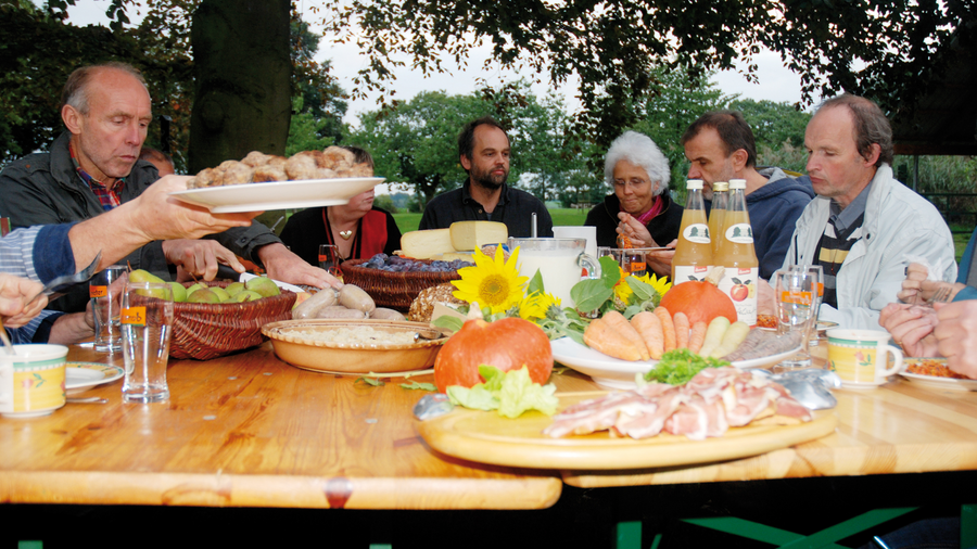 Menschen sitzen an einem Tisch und essen